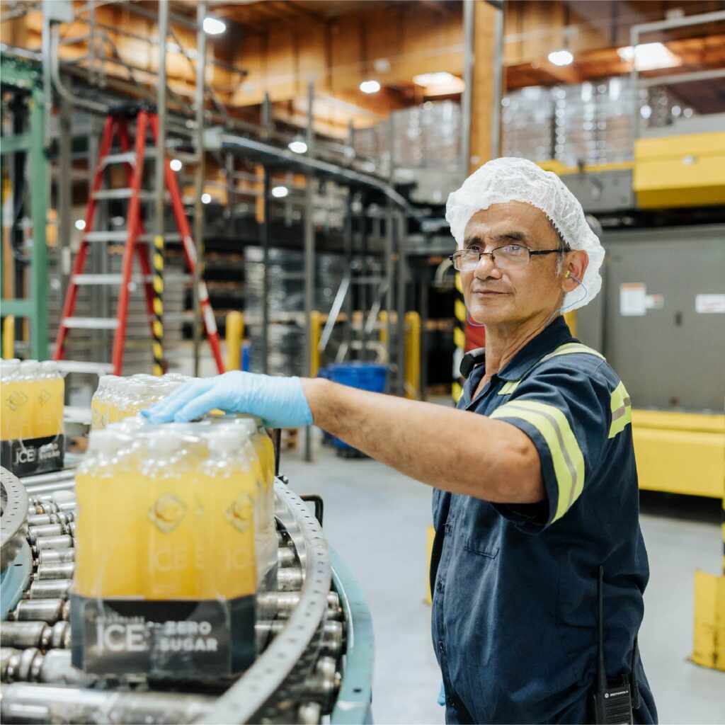 Talking Rain Beverage Company plant employee inspecting Sparkling Ice product on a conveyer belt at the bottling facility.
