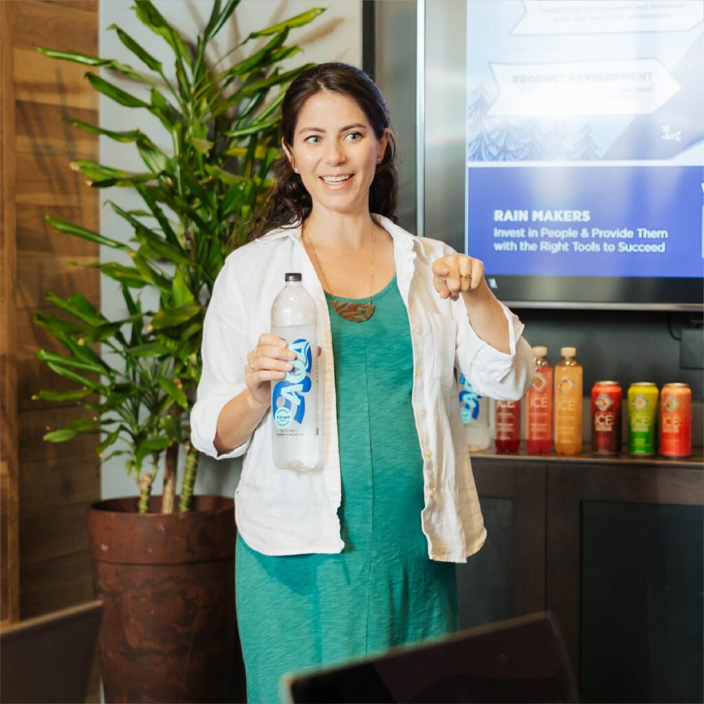 Talking Rain Beverage Company Technology employee holding a Talking Rain AQA bottle while giving a presentation.